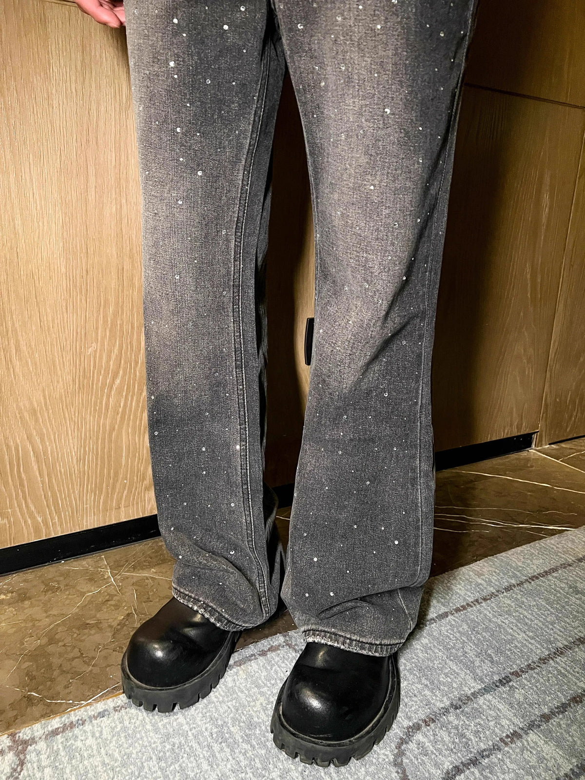 メンズのグレーのウォッシュドデニムパンツ。全体にクリスタル装飾が散りばめられ、センタープレス入り。裾はフレアシルエット。