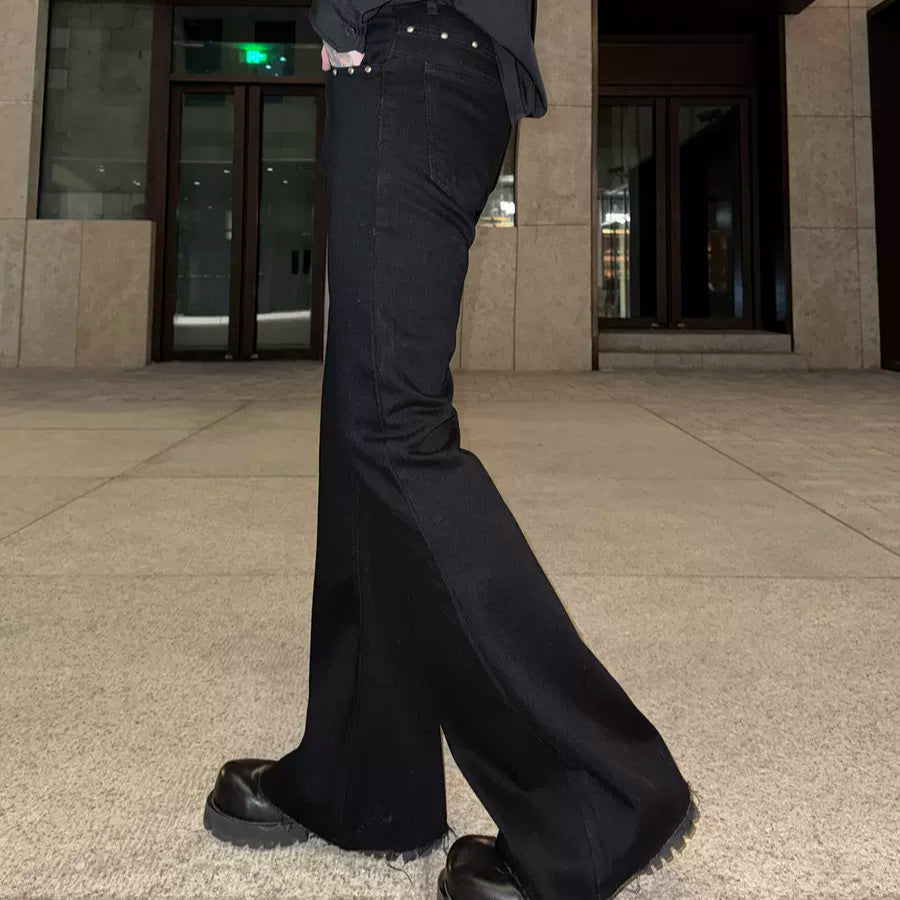 メンズの黒デニムのフレアパンツ。ウエストにスタッズ装飾があり、裾に向けて広がるシルエット。