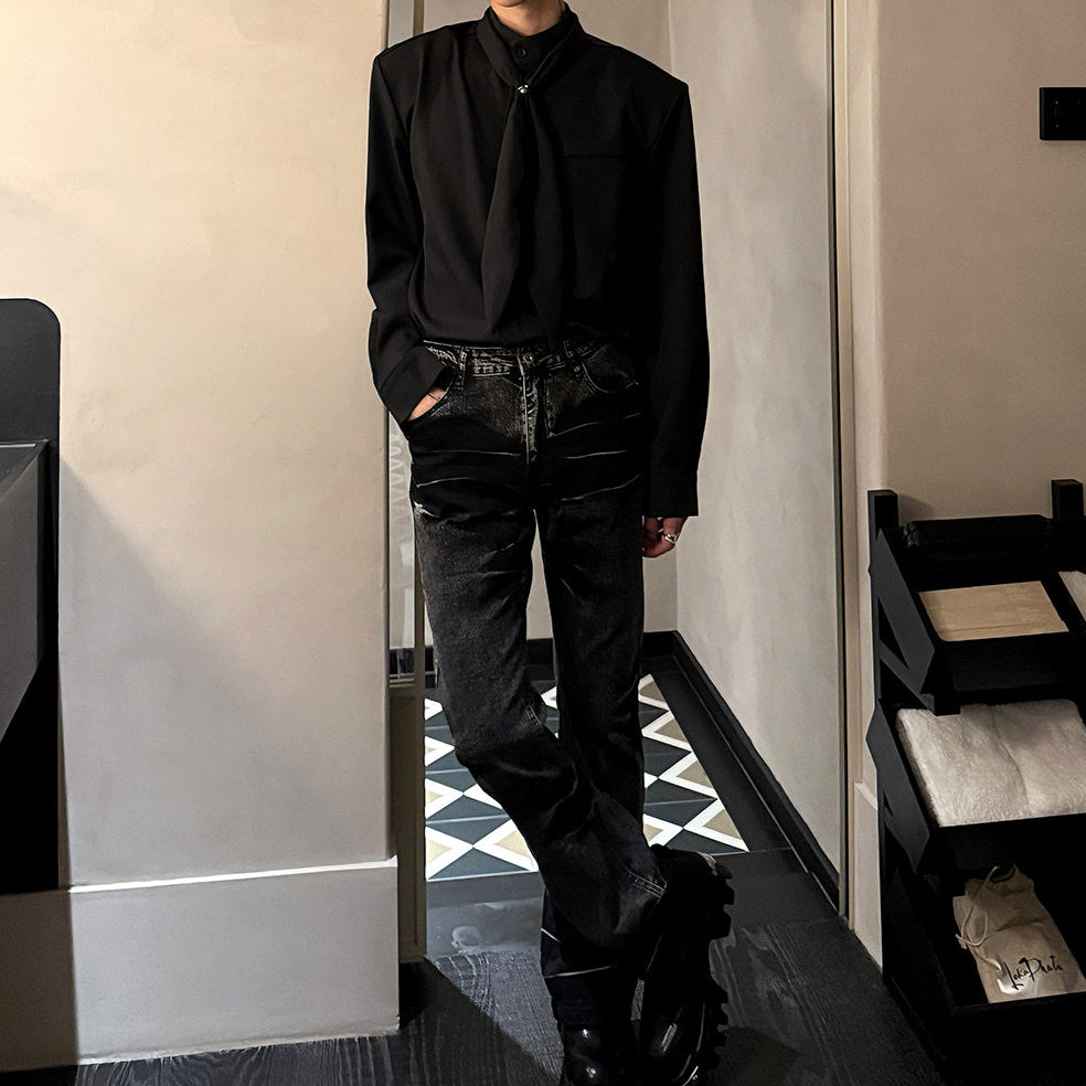 黒いシャツ。襟元にタイデザイン装飾、オーバーサイズシルエット。ダメージ入りの黒デニムパンツと合わせた着用画像。