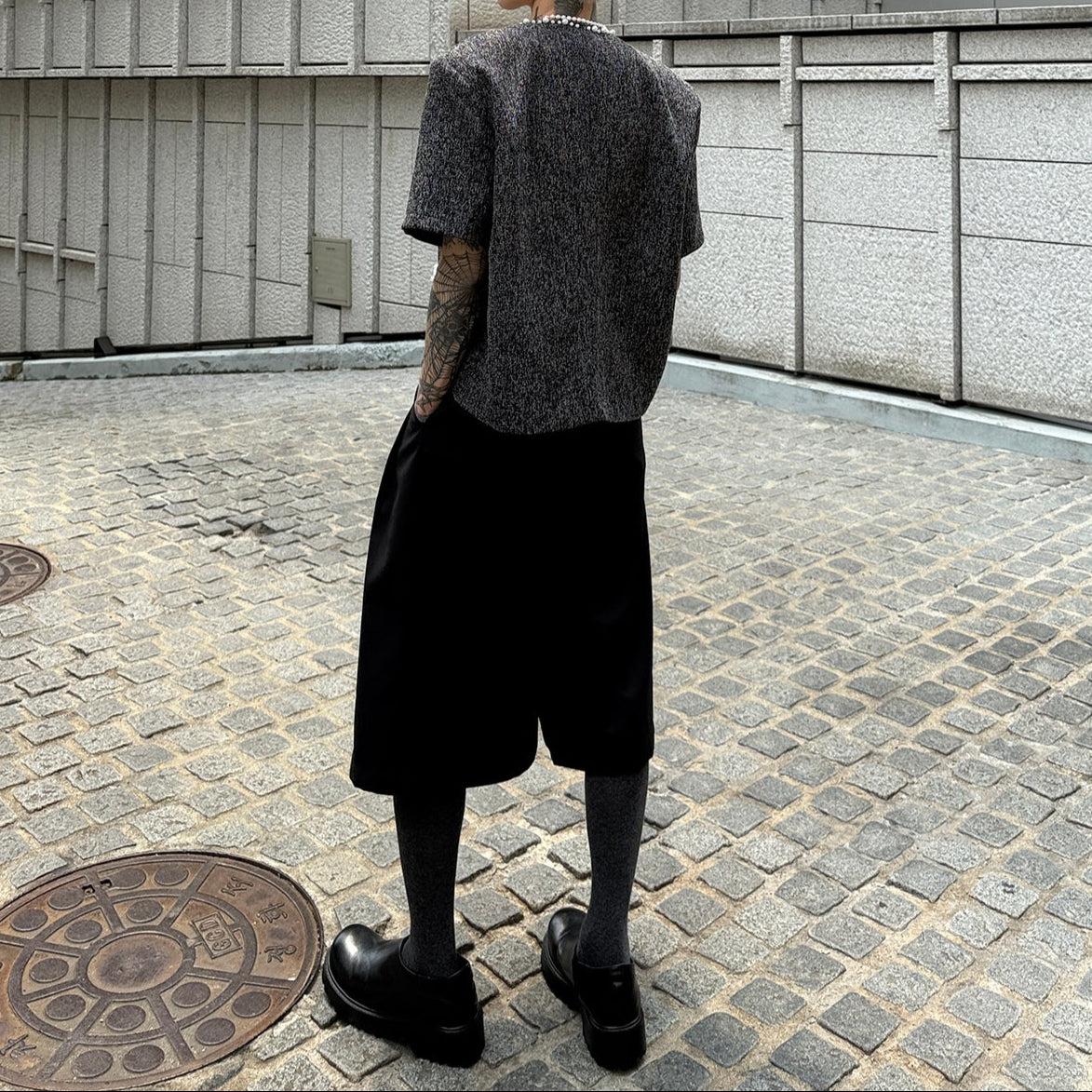 メンズの黒ツイードジャケットの後ろ姿全身。背面は無地で、着丈は短め。黒のワイドボトムと黒シューズを合わせる