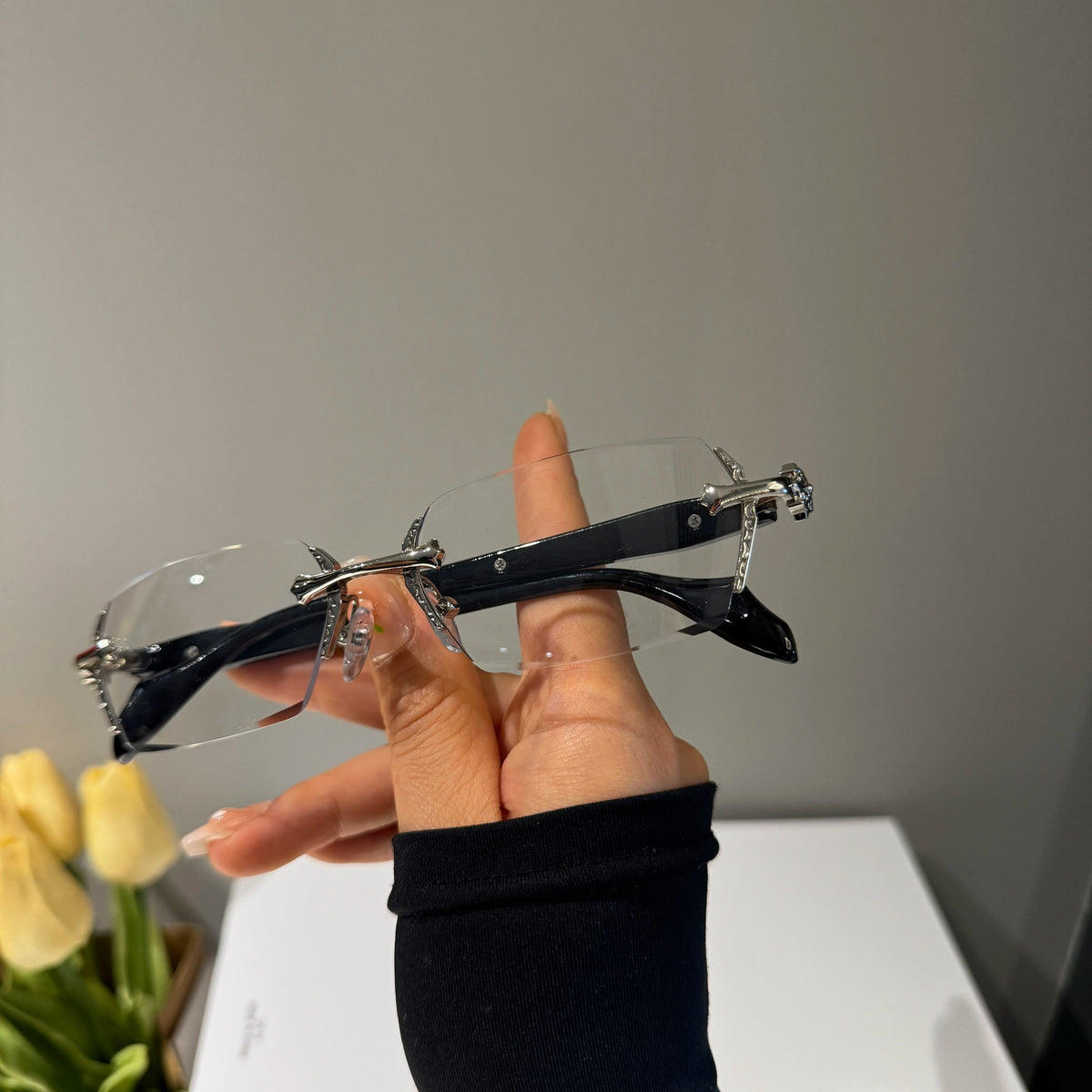 メンズの銀色の金具のリムレス眼鏡を斜めから撮った画像。縁のない無色のレンズと黒いテンプル、側面の細かな装飾が見える。