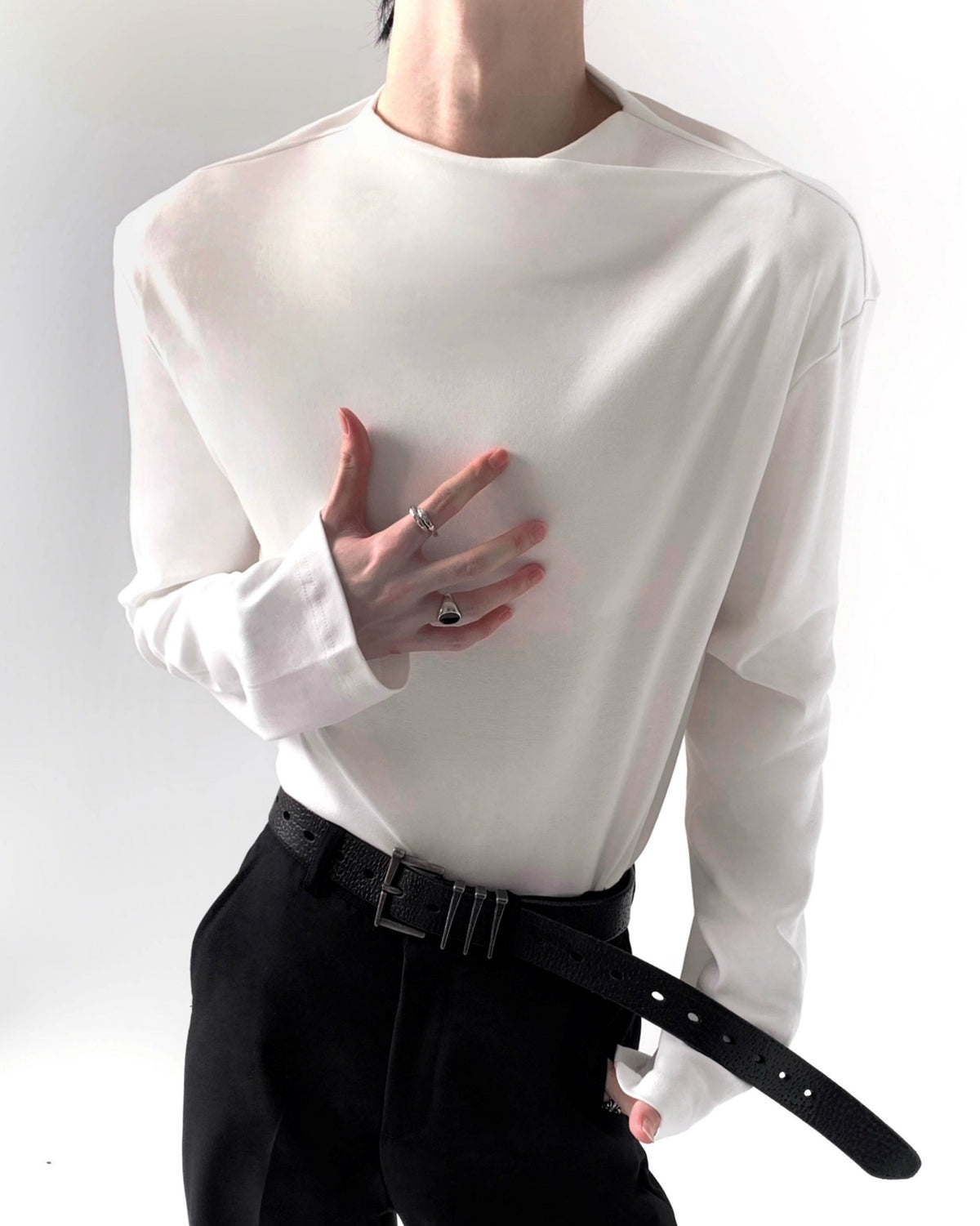 白いクルーネックロングスリーブカットソー。柔らかく落ちる素材感で、胸部分にドレープが自然に寄る。