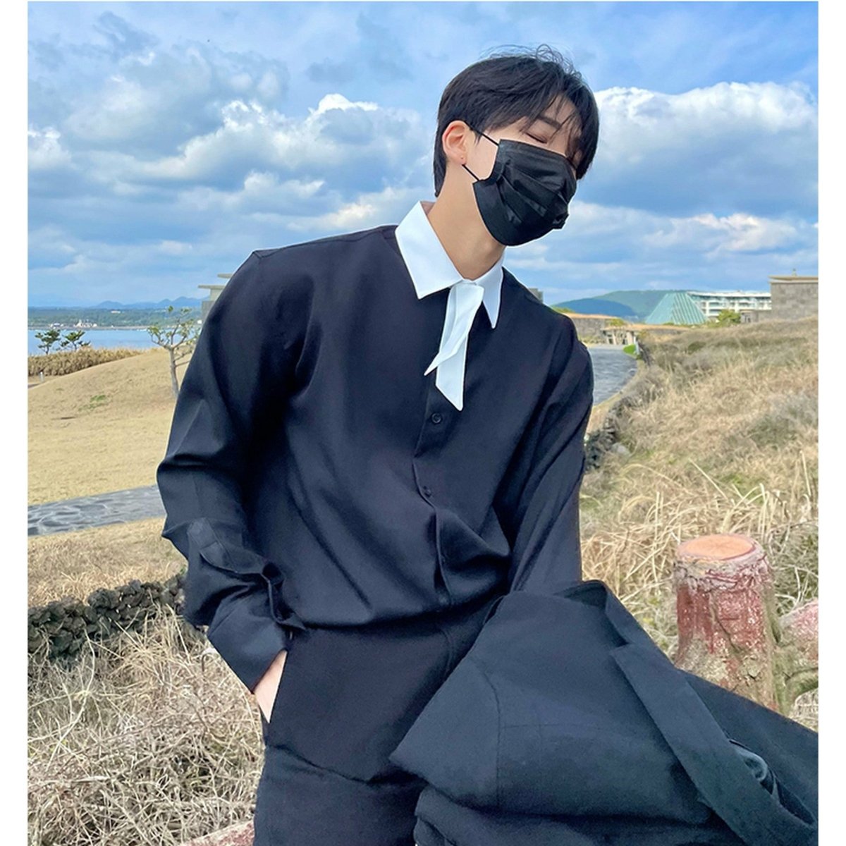 黒のカジュアルシャツ。白いスプレッドカラーと白いリボンタイを合わせたコーディネート。オーバーサイズのシルエットで、ゆったりとした袖と身幅が特徴。