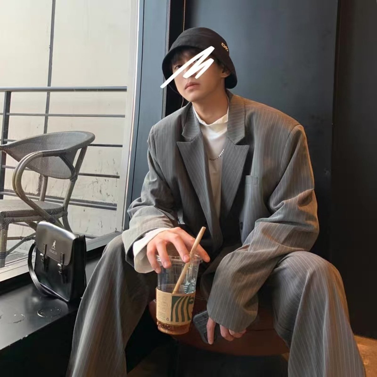 グレー系の細ストライプ柄オーバーサイズブレザーとワイドパンツのセットアップ。ノーカラーで開襟、内側にクリーム色のシャツを合わせた着用例。