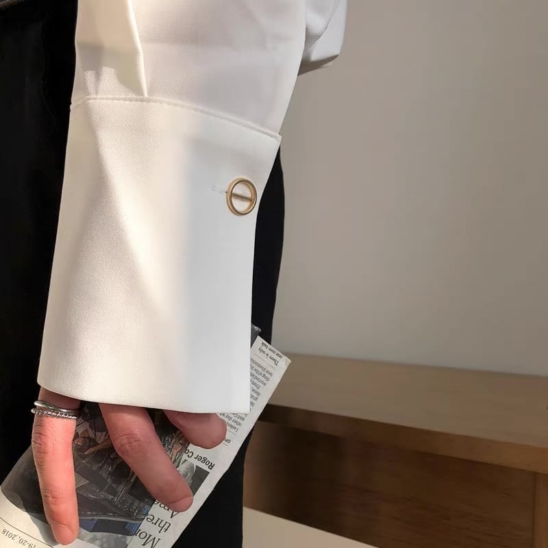 白のカジュアルシャツ。半袖でノーカラー、ゴールド金具付きスリット、腰部分にゴールド丸カン装飾。