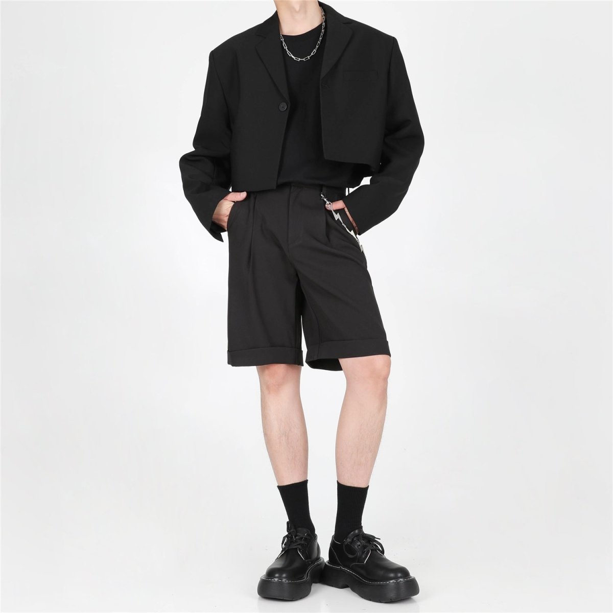 黒のショートジャケット。シングルブレストで衿と前身頃に切替があり、オーバーサイズなシルエット。黒のショートパンツとセットアップで着用。