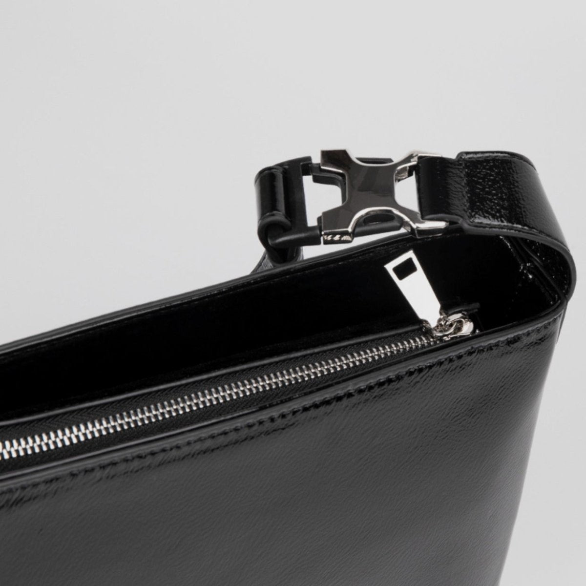 メンズの黒レザー製のショルダーバッグ。金属バックル付きの幅広ストラップと、メタルファスナー、内側のホワイトロゴラベルが特徴。