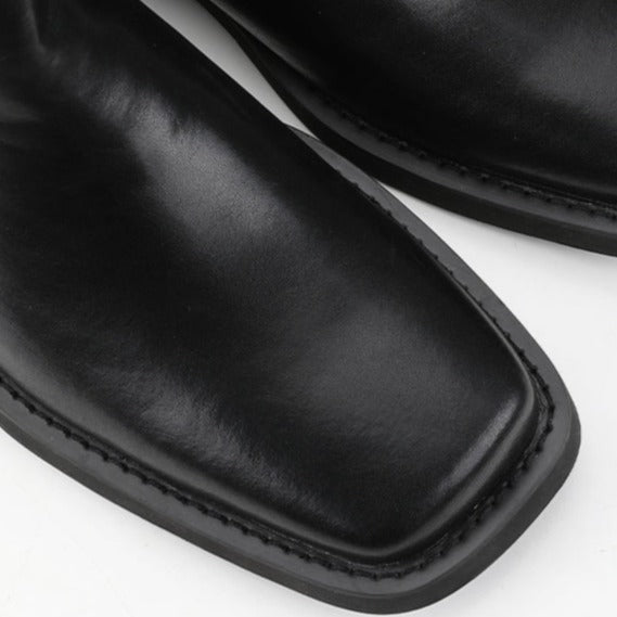 メンズの黒レザーのスクエアトゥシューズ。つま先が角張った形状で、スムースレザーの素材感が見える。